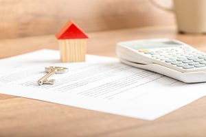 Contract, house keys and calculator on a table 