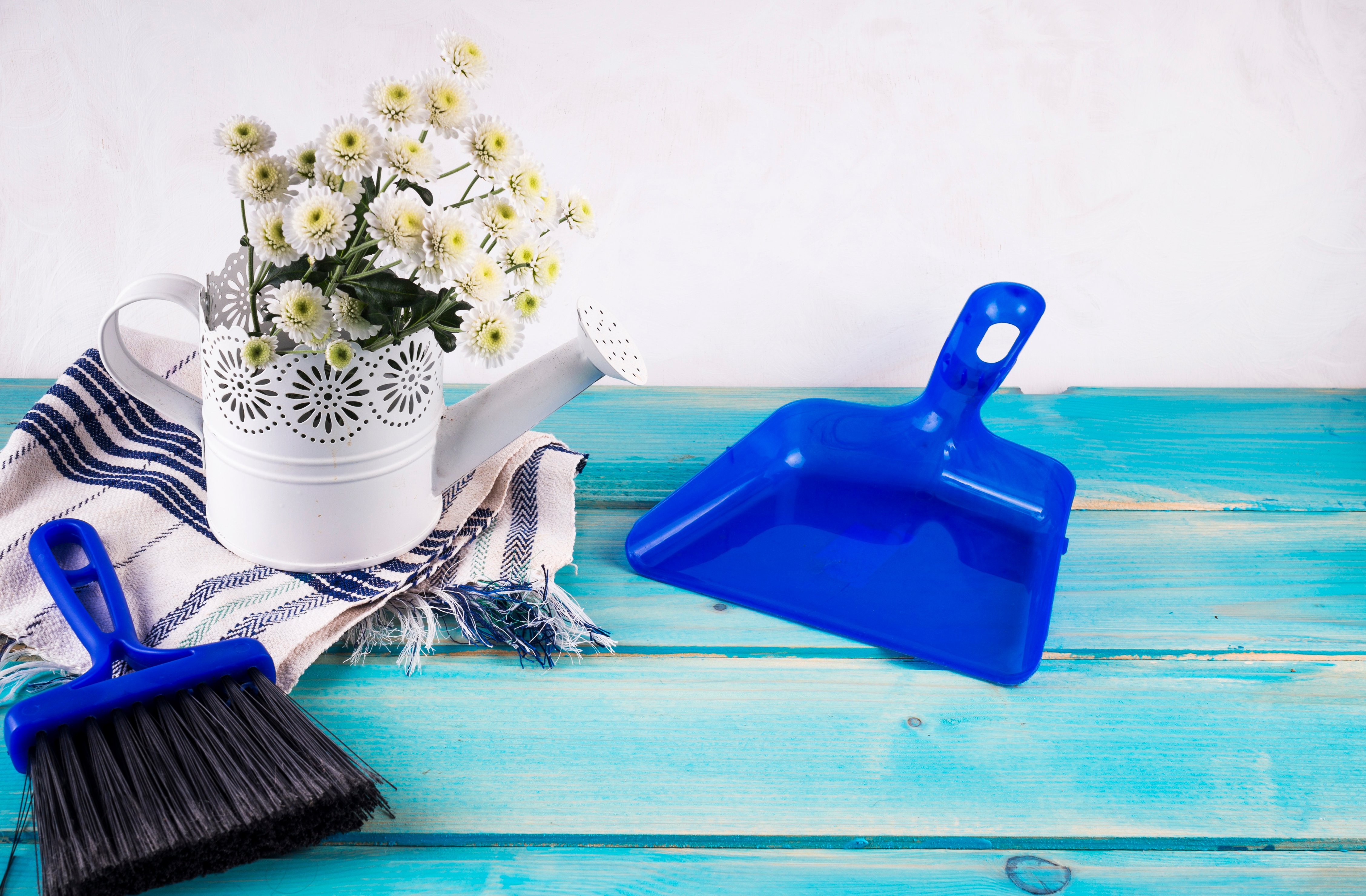 bunch-fresh-flowers-ornamental-watering-can-near-brush-dustpan